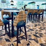 High-top bar stools with patterned backs and blue seats in a modern indoor setting.