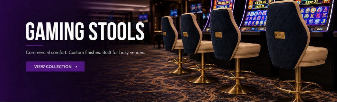 Promotional banner for gaming stools, showing several tall swivel chairs with dark blue upholstered backs and cream seats on gold bases, placed in a casino-style interior with slot machines and a purple 'VIEW COLLECTION' button.